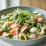 Creamy smoked salmon pasta salad with arugula, peas, and asparagus in a bright kitchen