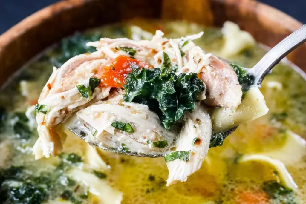 Close-up spoonful of keto chicken soup with chicken and greens