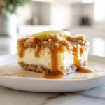 Caramel Apple Cheesecake Bars: The Ultimate Fall Dessert You’ll Crave All Year 8 Close-up of caramel apple cheesecake bars with caramel drizzle on a white plate in a modern kitchen