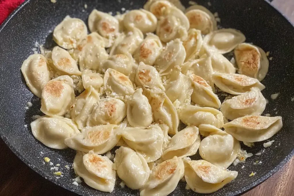 Frozen dumplings added to a skillet for pan-fried dumplings with sour cream