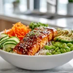 Honey Sriracha Salmon Bowls 7 Honey Sriracha Salmon Bowl hero image showing glazed salmon over rice with fresh vegetables and sesame garnish.