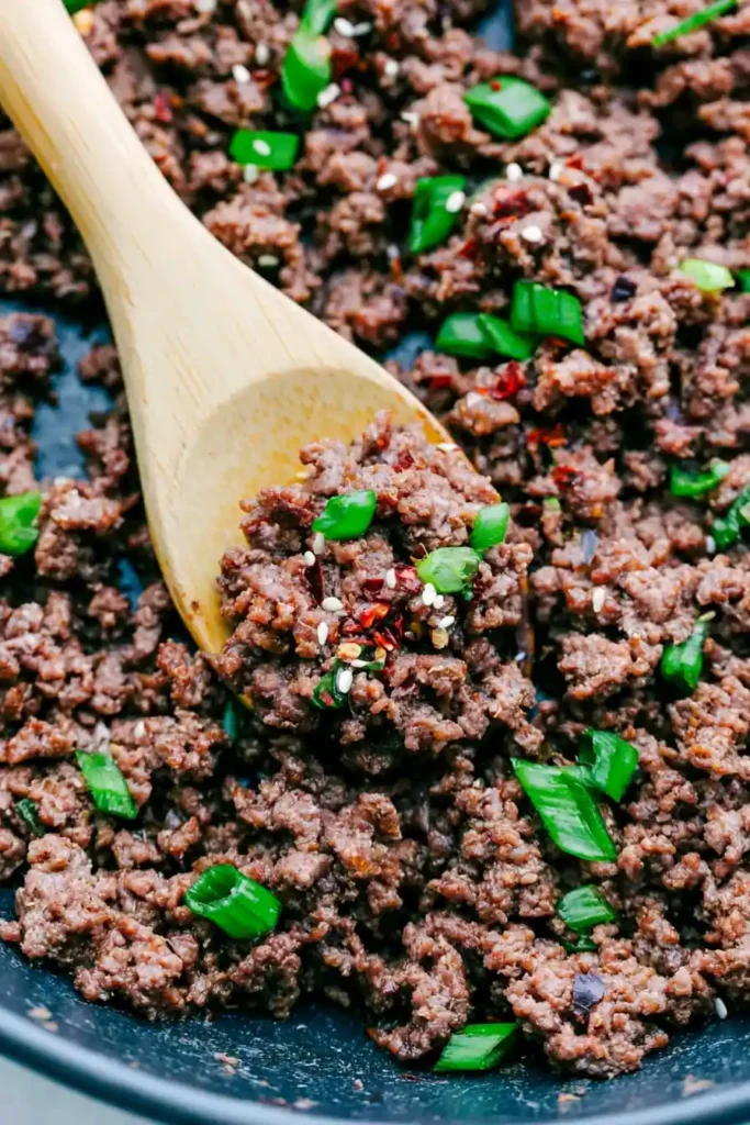 Korean Ground Beef Bowl for a Fast Weeknight Dinner 3 Glossy Korean Ground Beef Bowl filling with sesame seeds and green onions in a wooden spoon