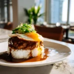 Authentic Loco Moco Recipe: A Taste of Hawaiian Comfort at Home 7 Photorealistic loco moco recipe plated with rice, beef patty, brown gravy, and fried egg in a modern kitchen setting.