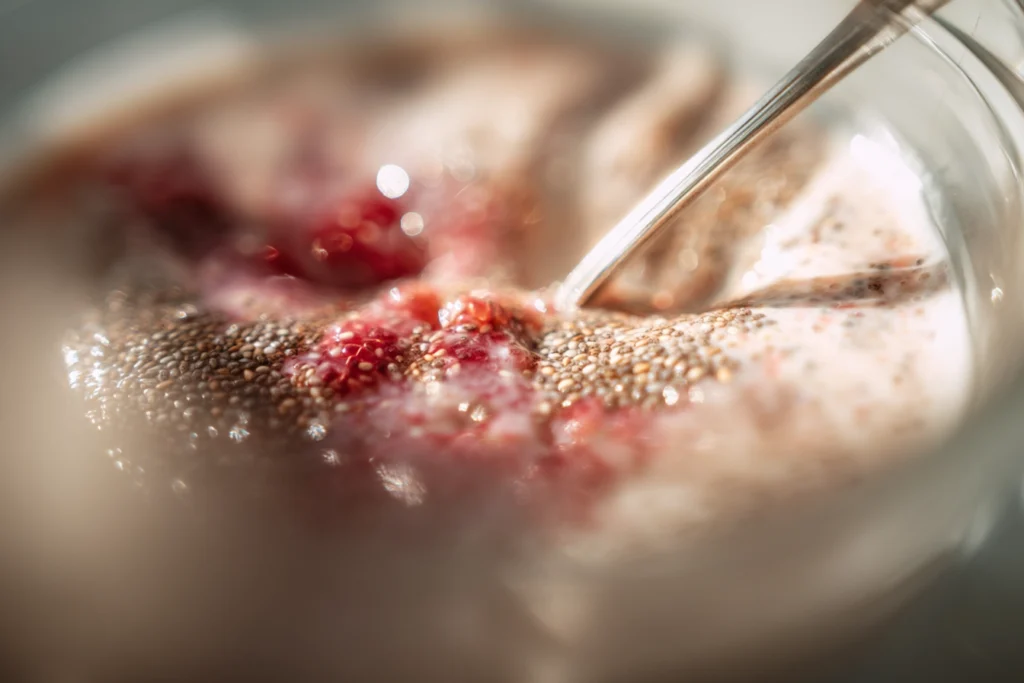 chia seeds being mixed into milk to prepare raspberry chia pudding