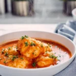 photorealistic bowl of tomato soup with cheddar bay dumplings in a modern kitchen