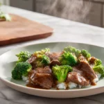 photorealistic beef and broccoli dish on a modern white plate in bright natural kitchen light