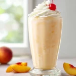 Chick-fil-A Peach Milkshake Copycat served with whipped cream, peach slices, and cherry