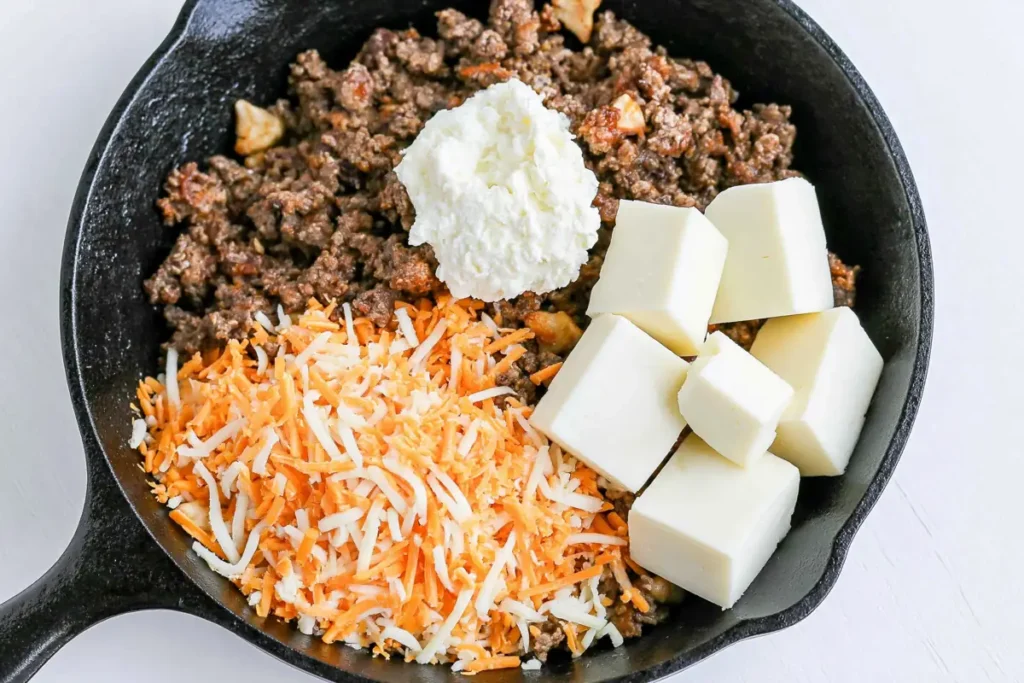Cowboy Queso ground beef with Velveeta cream cheese and shredded cheese in skillet