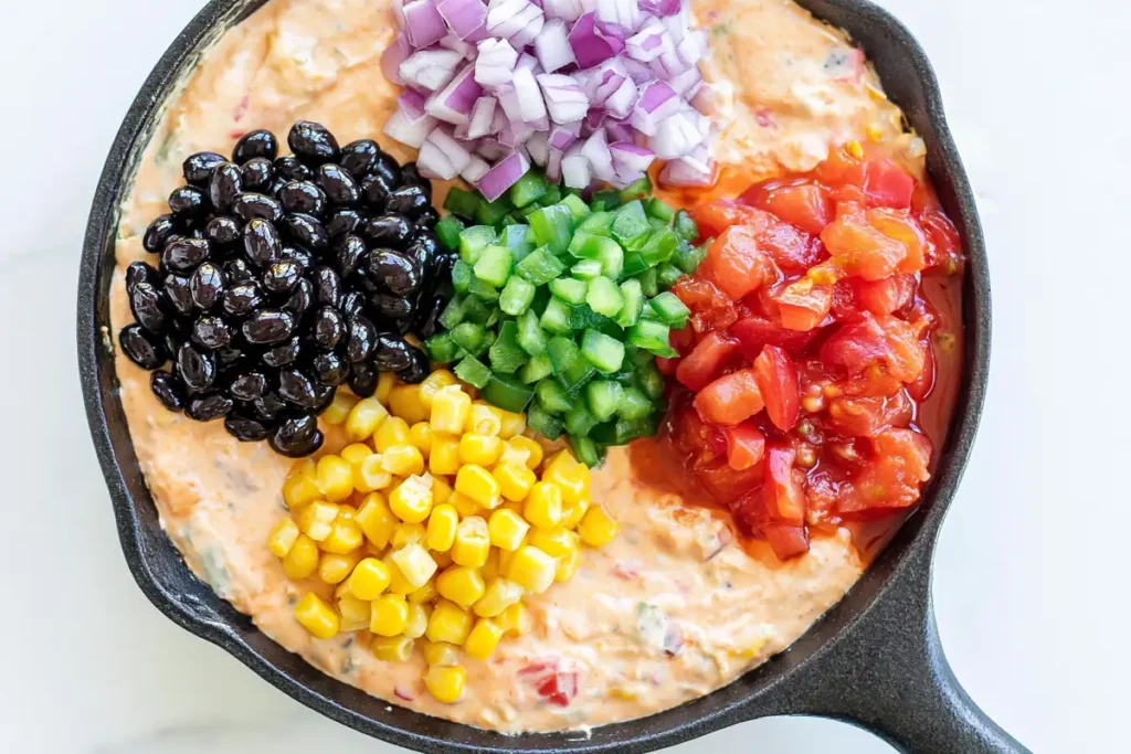 Cowboy Queso with black beans corn jalapeño red onion and Rotel added to melted cheese