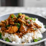 Finished Crock Pot Bourbon Chicken served with rice and garnish in modern kitchen