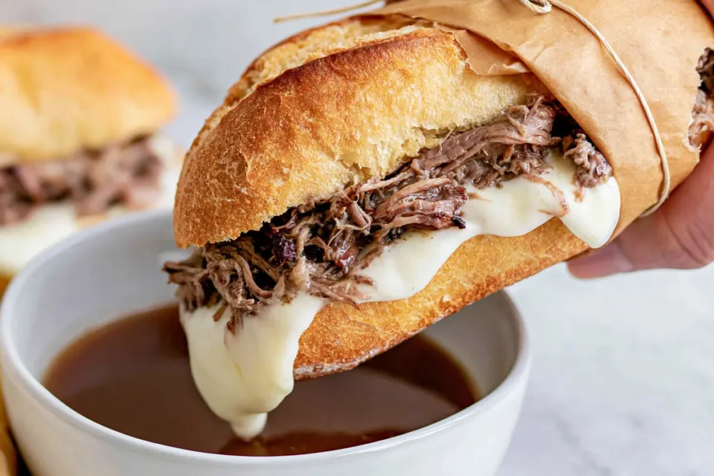 Crock Pot French Dip sandwich with melted provolone dipped into warm au jus