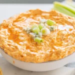 Crockpot Buffalo Chicken Dip in white bowl on marble counter with garnish