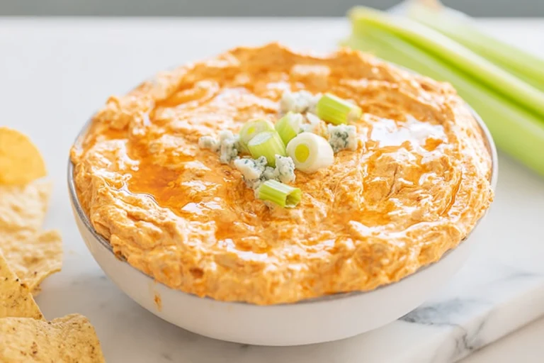 Crockpot Buffalo Chicken Dip in white bowl on marble counter with garnish