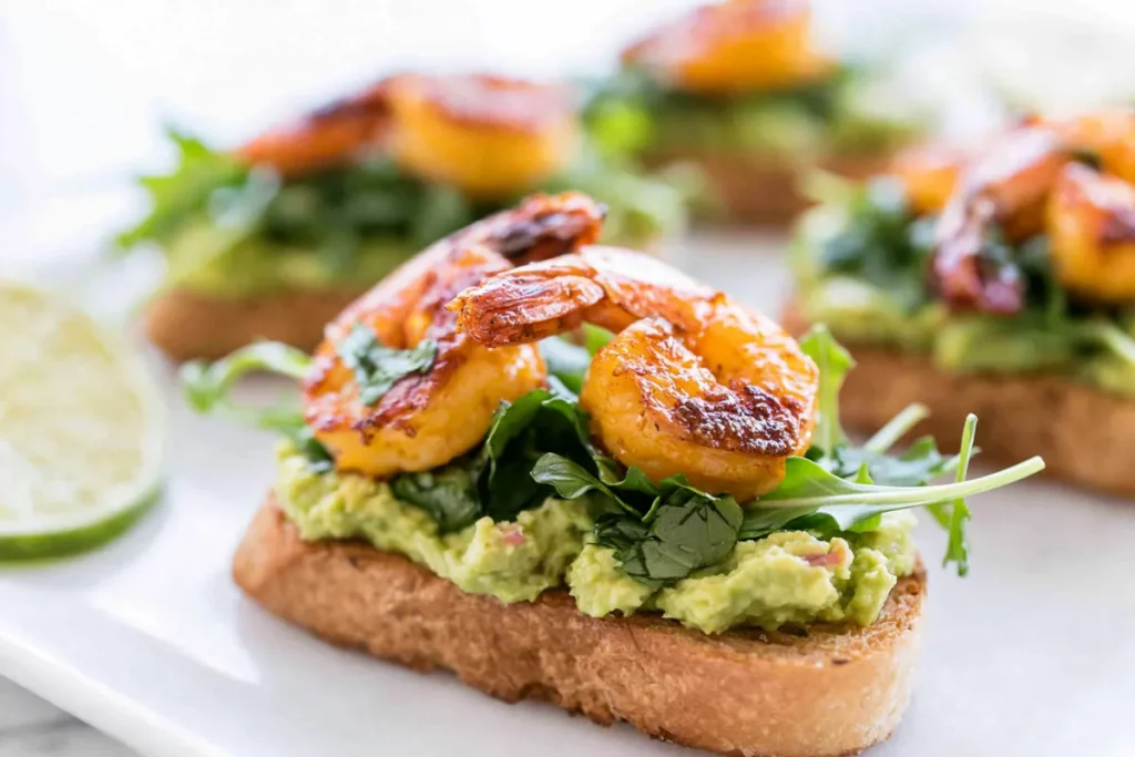 Garlic Shrimp Avocado Crostini for a Crisp, Creamy Party Bite 6 Garlic Shrimp Avocado Crostini with creamy avocado and arugula on toasted baguette