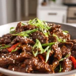 photorealistic image of keto mongolian beef on plate with sesame seeds and green onions