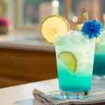 Mermaid Water Mocktail – Vibrant layered tropical drink with lime garnish and pineapple wedge.