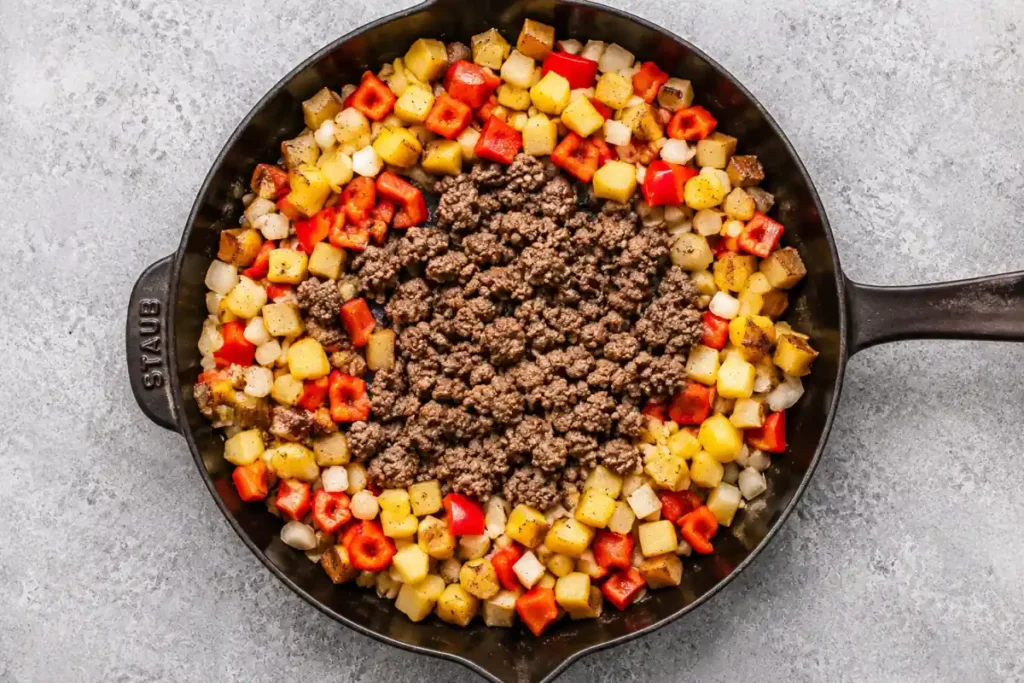 Mexican Ground Beef and Potato Skillet with Melted Cheese 5 Ground beef, onion, and red bell pepper cooking with potatoes for Mexican Ground Beef and Potato Skillet