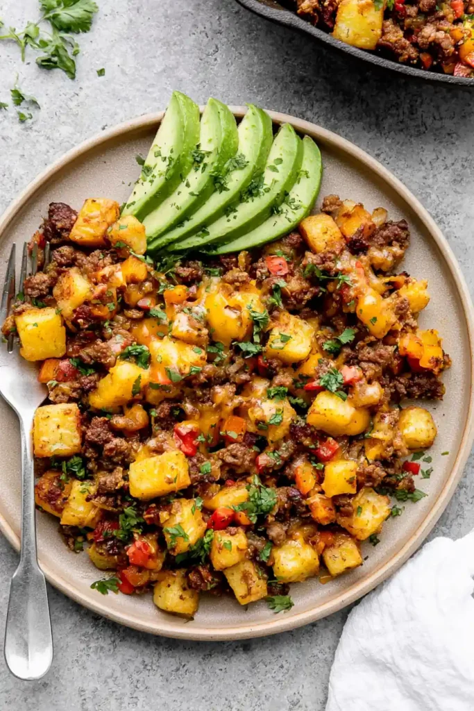 Mexican Ground Beef and Potato Skillet with Melted Cheese 11 Mexican Ground Beef and Potato Skillet plated with avocado in a warm family kitchen