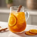 Hero shot of Orange Cinnamon Iced Tea in a modern kitchen with citrus and cinnamon garnish