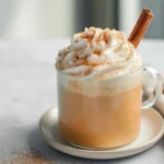 pumpkin spice milk served with whipped cream and cinnamon stick in modern kitchen