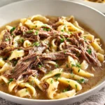 photorealistic bowl of slow cooker beef and noodles in a modern kitchen