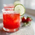 Strawberry Lime Mocktail Margarita in a modern glass with lime wedge and salted rim, vibrant red and green contrast.