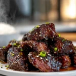Sweet and Sticky Steak Bites plated with glaze and sesame seeds in a modern kitchen