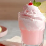 Whipped pink lemonade in a modern kitchen with whipped topping, mint, and lemon garnish.