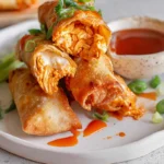 Buffalo Chicken Egg Rolls plated with dipping sauce on a modern kitchen counter