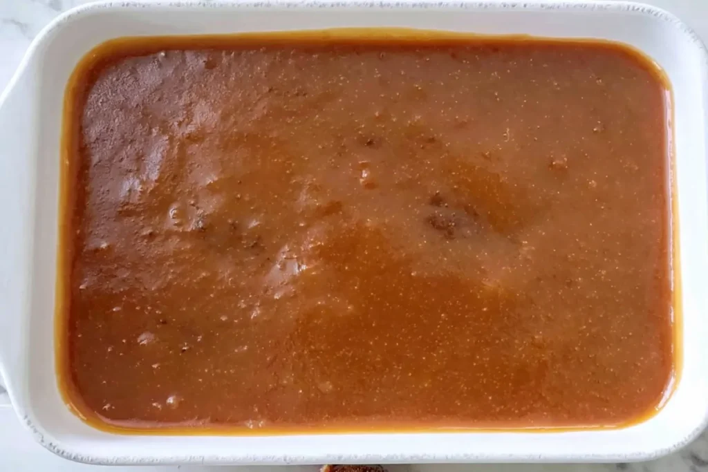 Buttery caramel base for Overnight Crème Brûlée French Toast in a white baking dish
