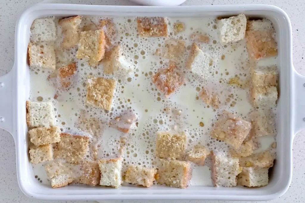 Custard mixture poured over bread cubes for Overnight Crème Brûlée French Toast