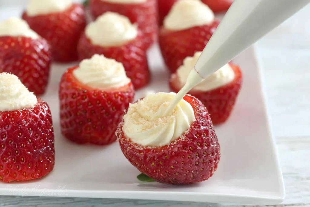 macro shot of filling strawberries with cheesecake mixture for strawberry cheesecake bites