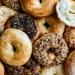 Mohamed Ayad's Homemade Bagels Recipe with golden chewy bagels on a wooden board