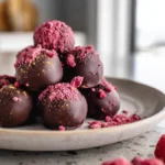 raspberry truffles plated on a modern plate with cocoa powder