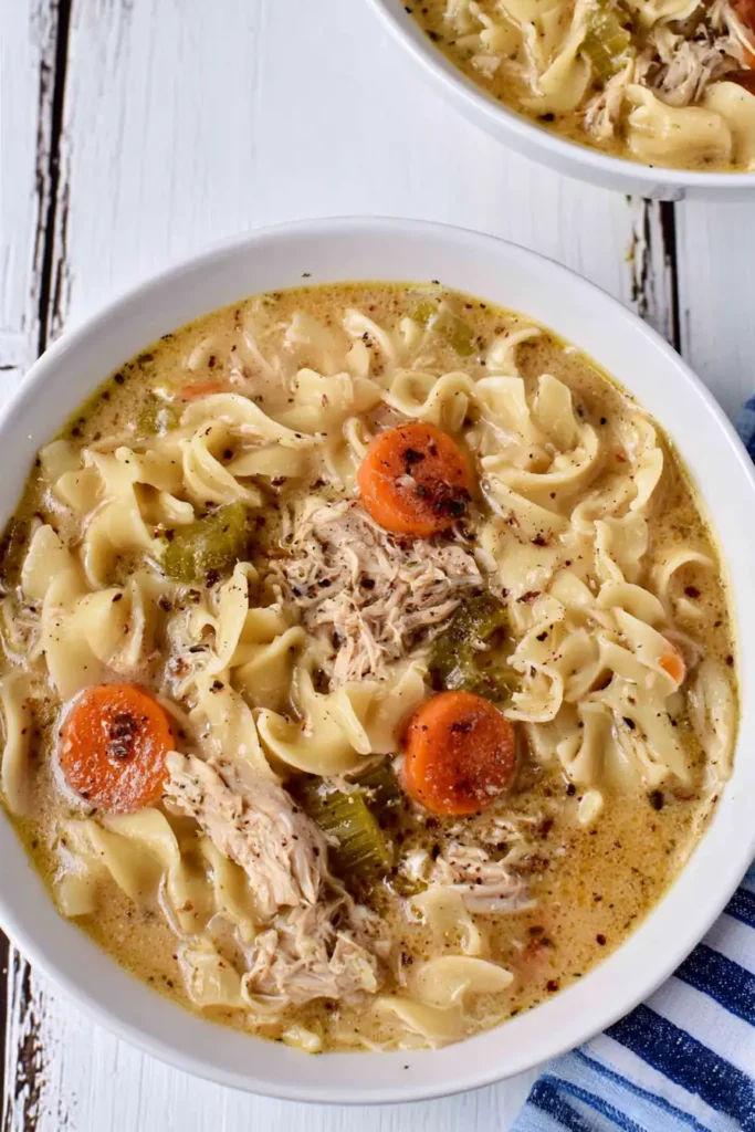 Creamy Chicken Noodle Soup for Cozy Winter Nights 8 Finished creamy chicken noodle soup in a Dutch oven beside sliced bread