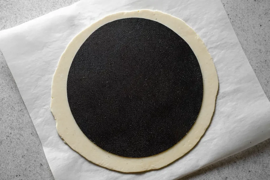 Rolling shortcrust dough between parchment sheets for walnut tart shell
