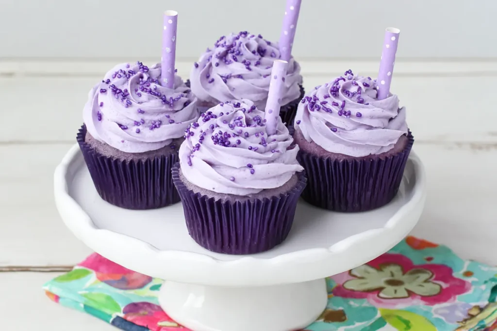 Mohamed Ayad's Grape Soda Cupcakes Recipe on a white cake stand with purple frosting