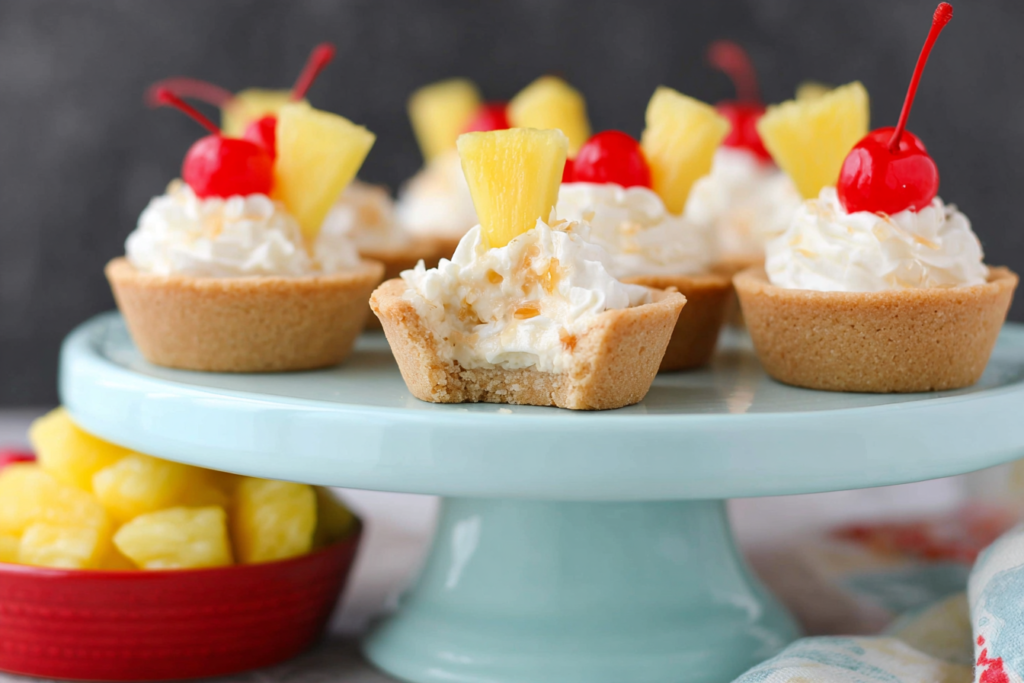 Bitten Pina Colada Cookie Cups with creamy pineapple filling on a pale blue serving stand