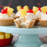 Bitten Pina Colada Cookie Cups with creamy pineapple filling on a pale blue serving stand