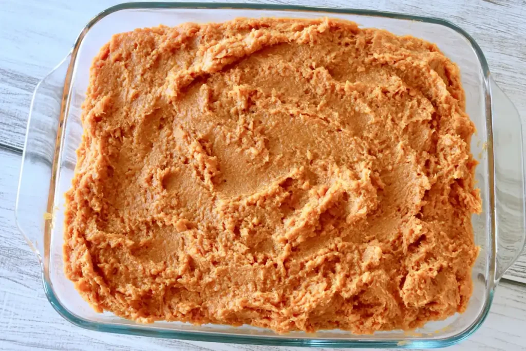 Seasoned bean layer spread in a baking dish for American flag layered taco dip