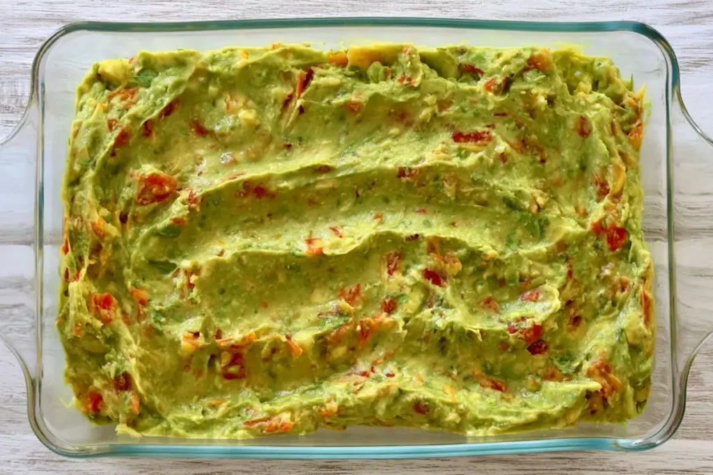 Guacamole layer spread over refried beans for American flag layered taco dip