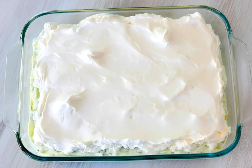 Sour cream layer for American flag layered taco dip in a glass baking dish