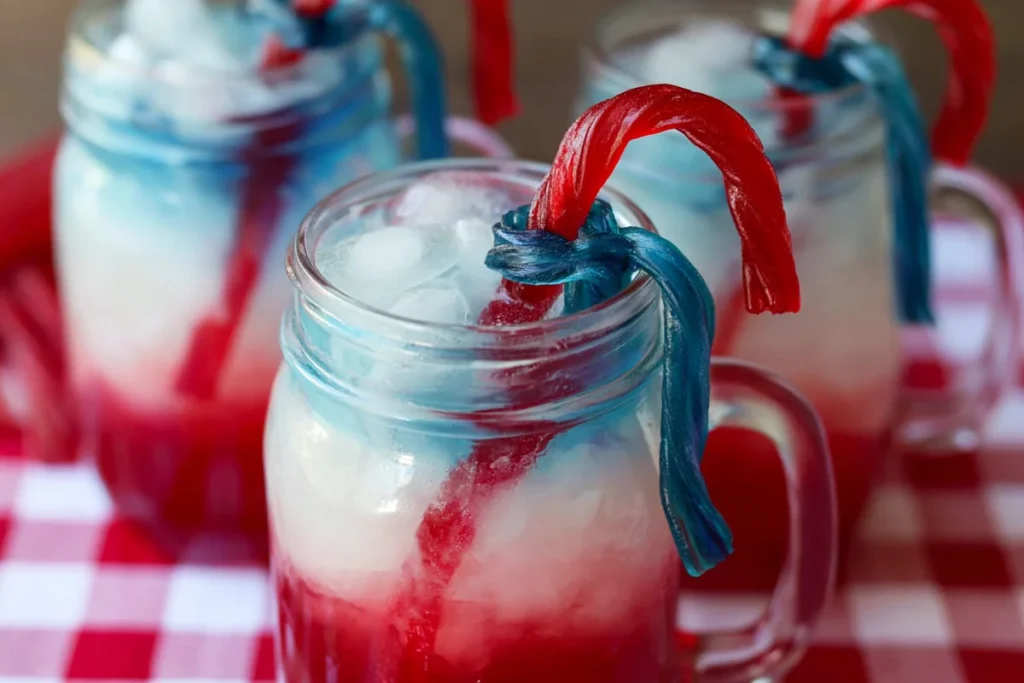 Layered patriotic punch in a mason jar with ice and candy straw