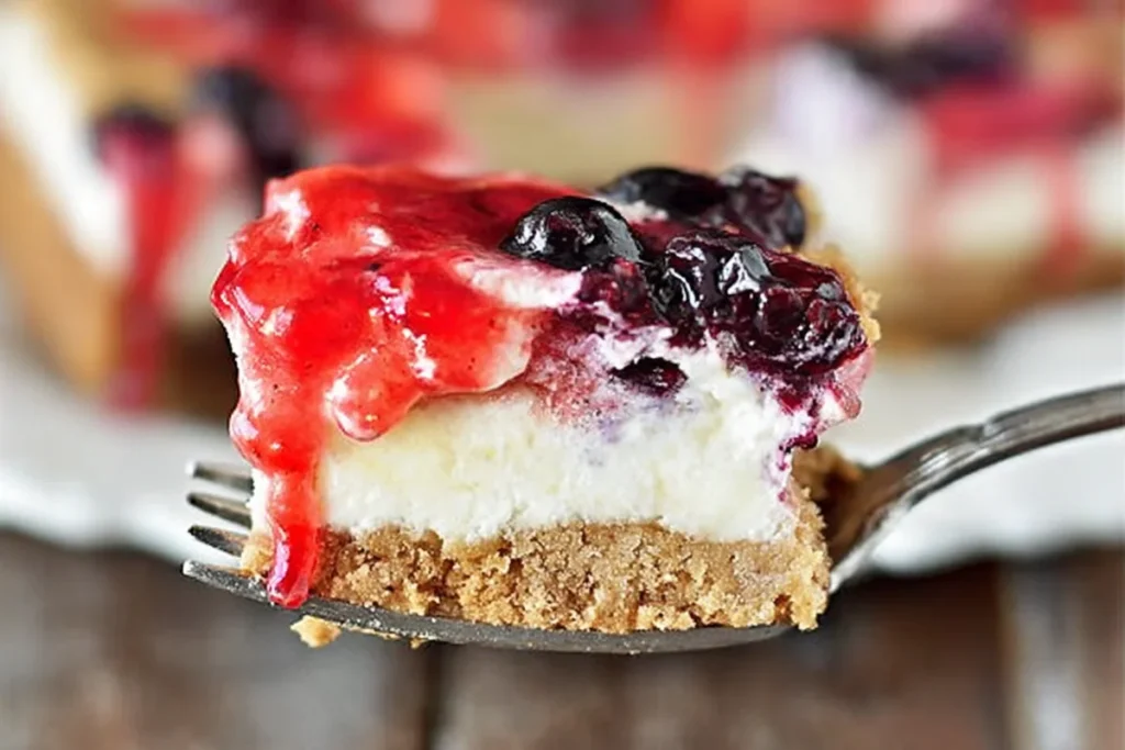 Mixed berry yum yum bite with strawberry blueberry layers and graham cracker crust