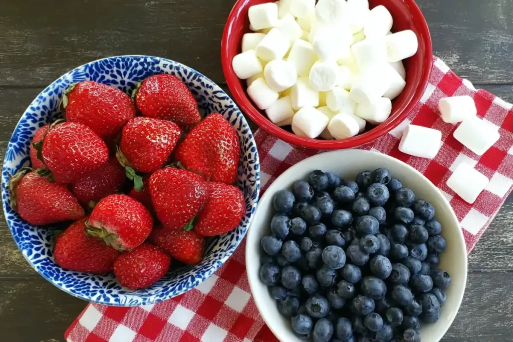 Ingredients for red white and blue cheesecake salad with strawberries blueberries and mini marshmallows